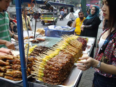 Bangkok food seller prepares a batch of satay sticks for the passing shoppers