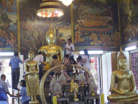 Worshippers apply gold leaf to the Buddha image